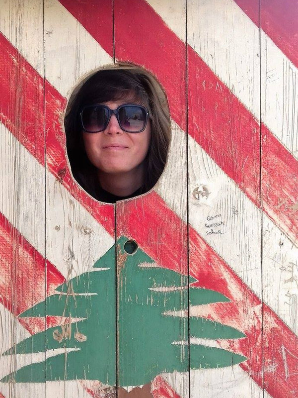 Jen Condon, founder of Oddball Tours, peeking through a hole in a painted wooden cut-out
